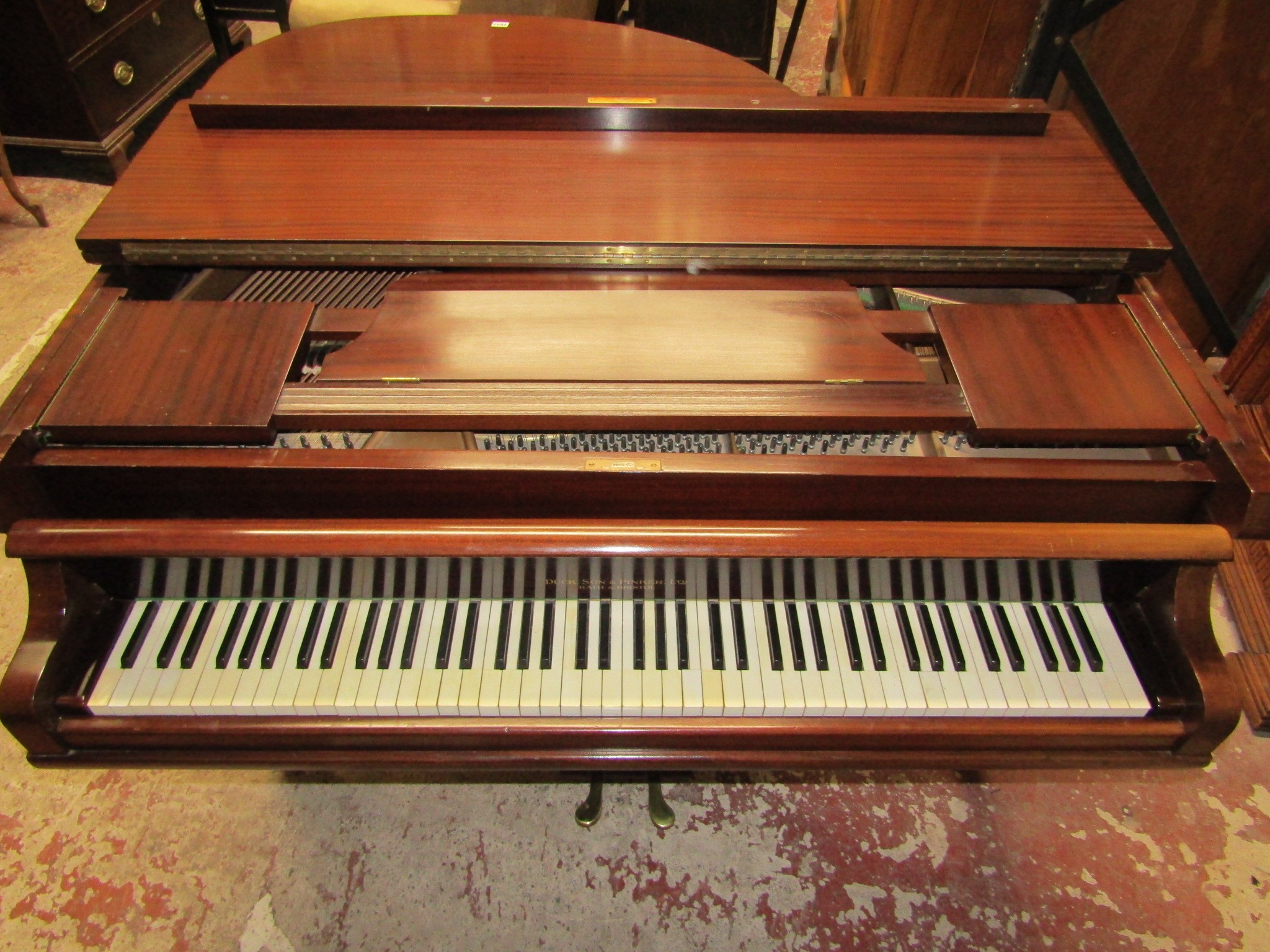 A Baby Grand Piano retailed by Duck Son & Pinker in a polished mahogany cased raised on three square