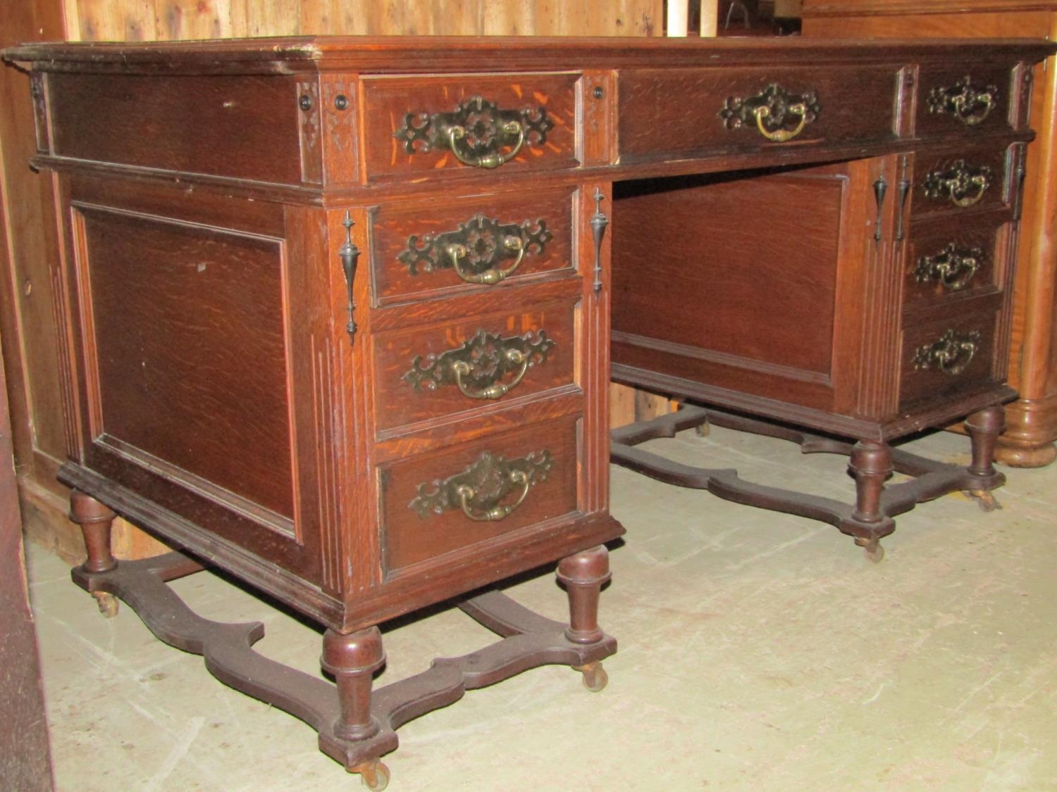 A 19th century oak kneehole twin pedestal desk with inset leather top over an arrangement of nine