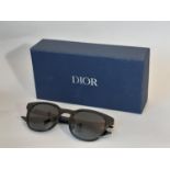 A pair of mens sunglasses by Christian Dior Homme, appear unused, with envelope style case in black