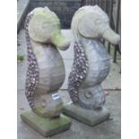 A pair of weathered cast composition stone garden ornaments in the form of sea horses with