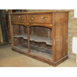 A rustic stripped pine kitchen dresser base fitted with two frieze drawers over an open shaped shelf