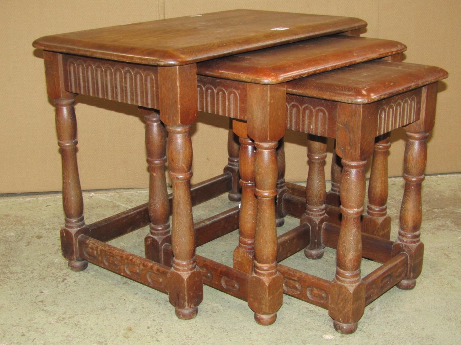 A nest of three oak graduated occasional tables in the old English style, outer table 61 cm wide x