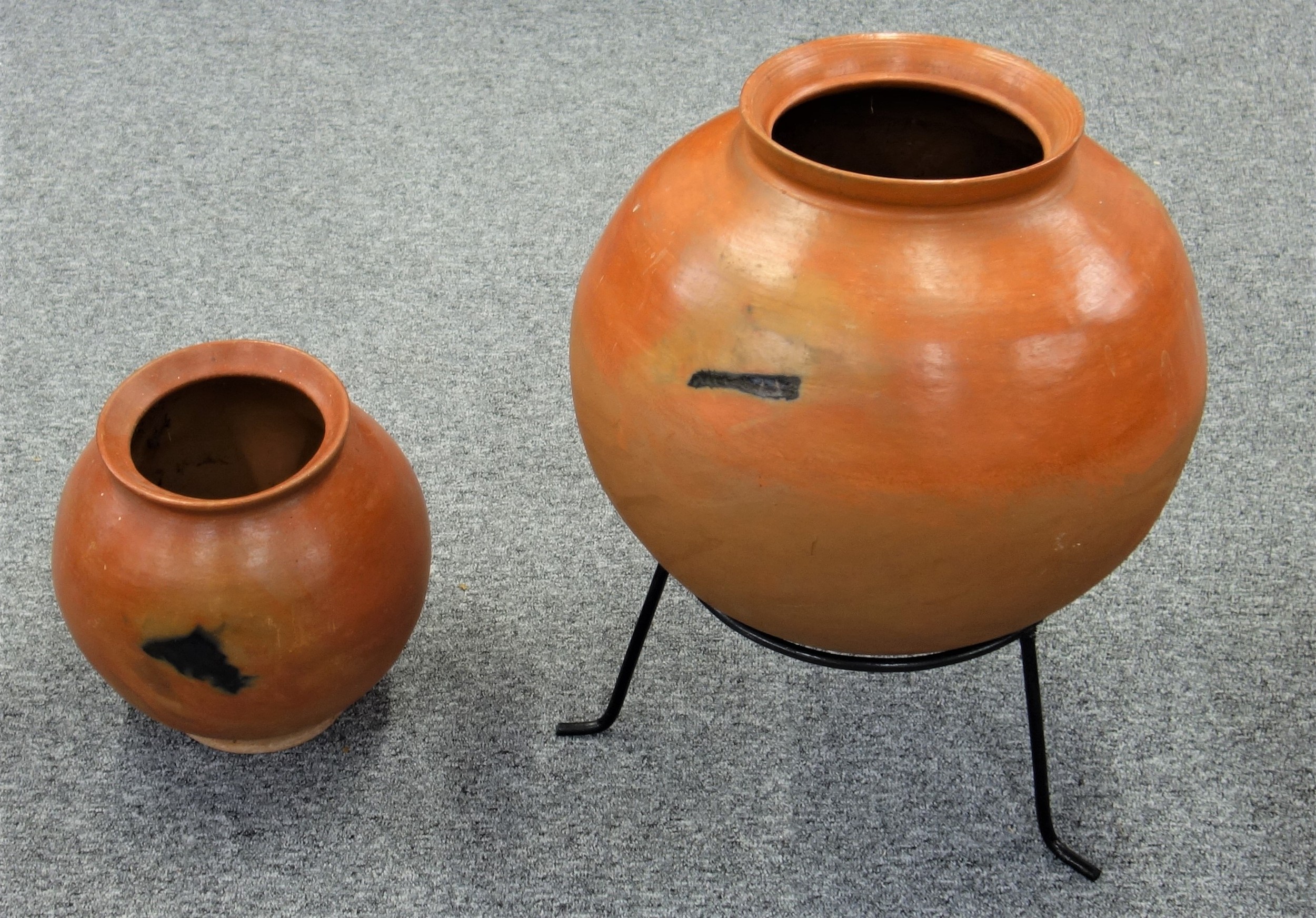 Large African terracotta cooking pot Dia. 48cm, H. 46cm, with a metal stand, and another similar pot