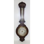 An Edwardian oak aneroid barometer/ thermometer, the case with shell and foliate carved