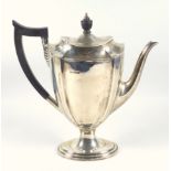 George V silver coffee pot of shaped tapering oval form, with a scroll spout and ebonized handle, on