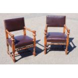 A pair of early 20th century oak barley twist open arm elbow chairs with brown leather brass studded