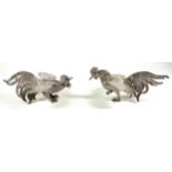 Pair of Egyptian white metal models of fighting cocks, W. 18 cm and 15.5 cm, 640grs