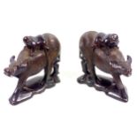 Pair of Oriental carved ebonized wood groups, each with a figure on a water buffalo, on a shaped