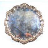 George V silver circular salver with a shell and scroll piecrust rim, on 3 claw and ball feet, by