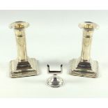 Pair of George V silver candlesticks, each with embossed floral swag and ribbon decoration, on a