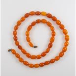 Amber oval bead necklace with barrel clasp, L 68cm, gross 44.7cm, in a pouch (2)