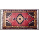 Persian rug, the madder field with a hooked medallion, spandrels and stylised floral decoration,