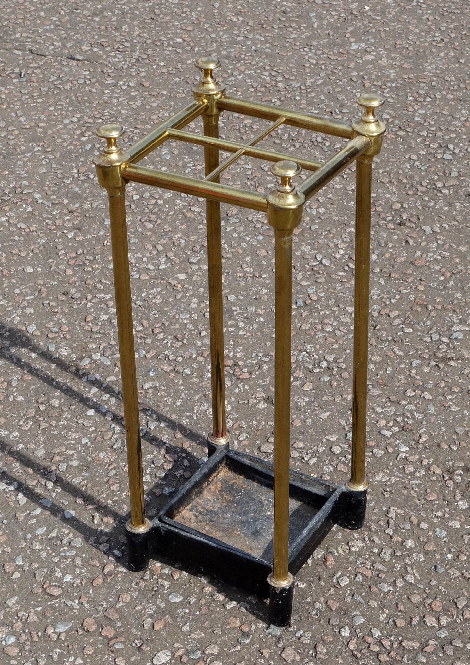 Victorian brass stick stand with grid top of 4 divisions and finials, set on a cast iron drip tray