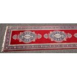 Persian runner, the madder field with a row of anchor medallions with stylised floral decoration,