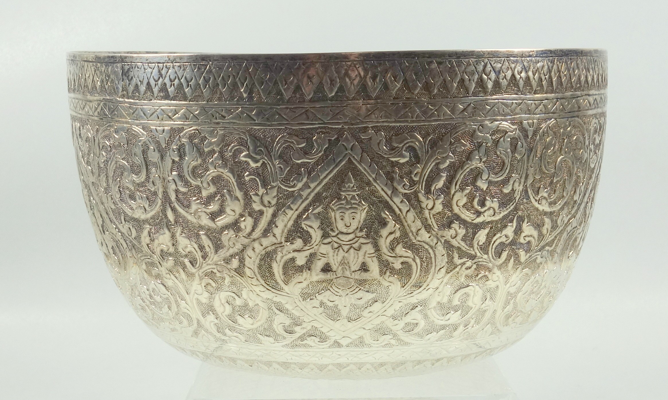 Burmese white metal circular bowl embossed with Buddhas and scrolling floral decoration, D 19cm,