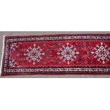 Persian runner, the madder field with a row of 5 lozenges and all-over stylised floral decoration,