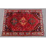 Persian rug, the madder field field with a triple lozenge medallion and all-over stylised floral