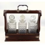 Edwardian oak tantalus with plated mounts and 3 square cut decanters, each with a faceted stopper, W