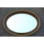 Edwardian bevelled oval wall mirror in a mahogany finish and gilt moulded acorn decorated frame,
