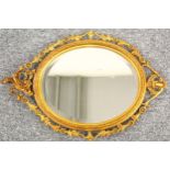Upright wall mirror with a bevelled oval plate, in a gilt moulded floral decorated frame, 79 x 55.
