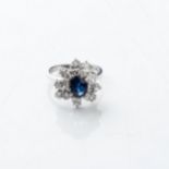 A SAPPHIRE AND DIAMOND CLUSTER RING Claw-set to the center with an oval sapphire weighing