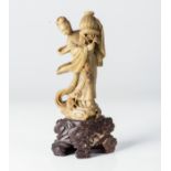 A CHINESE SOAPSTONE FIGURE OF GUAN-YIN Standing on Lingzhi-shaped clouds clad in a billowing robe,