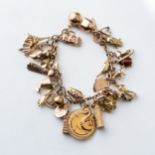 A GOLD CHARM BRACELET Curb link, with various international charms including a 22ct gold coin,