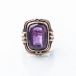 AN AMETHYST RING Bezel-set to the center with an emerald-cut amethyst weighing approximately 15