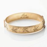 A GOLD PLATED METAL CORE BANGLE Hinged, 12mm wide, with floral engraving
