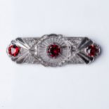 A DIAMOND AND GARNET BROOCH Claw-set to the center and sides with 3 round brilliant-cut garnets