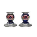 A PAIR OF MOORCROFT TUDRIC PEWTER 'PANSY' PATTERN CANDLESTICKS, 1920s