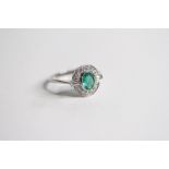 Platinum oval bezel set Emerald in a diamond surround with baguettes leading of the the shank. E0.