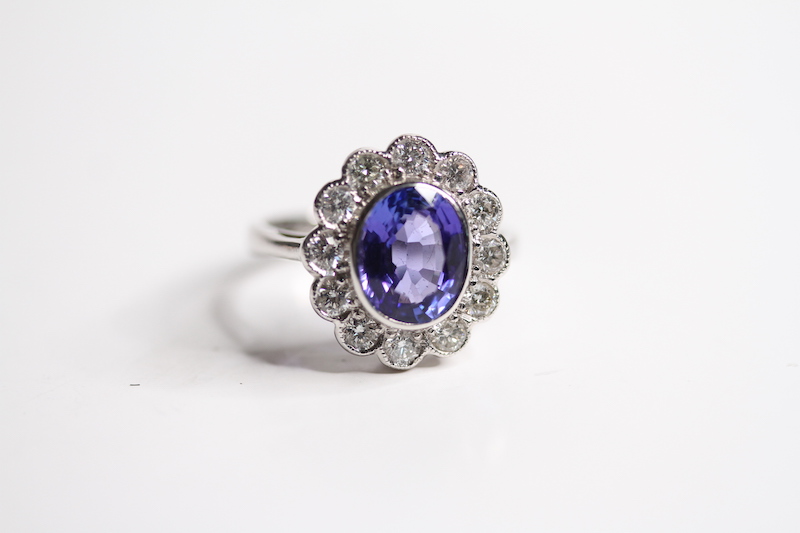18ct Oval bezel set tanzanite and diamond cluster ring, 12 diamonds in the outer cluster TZ Est