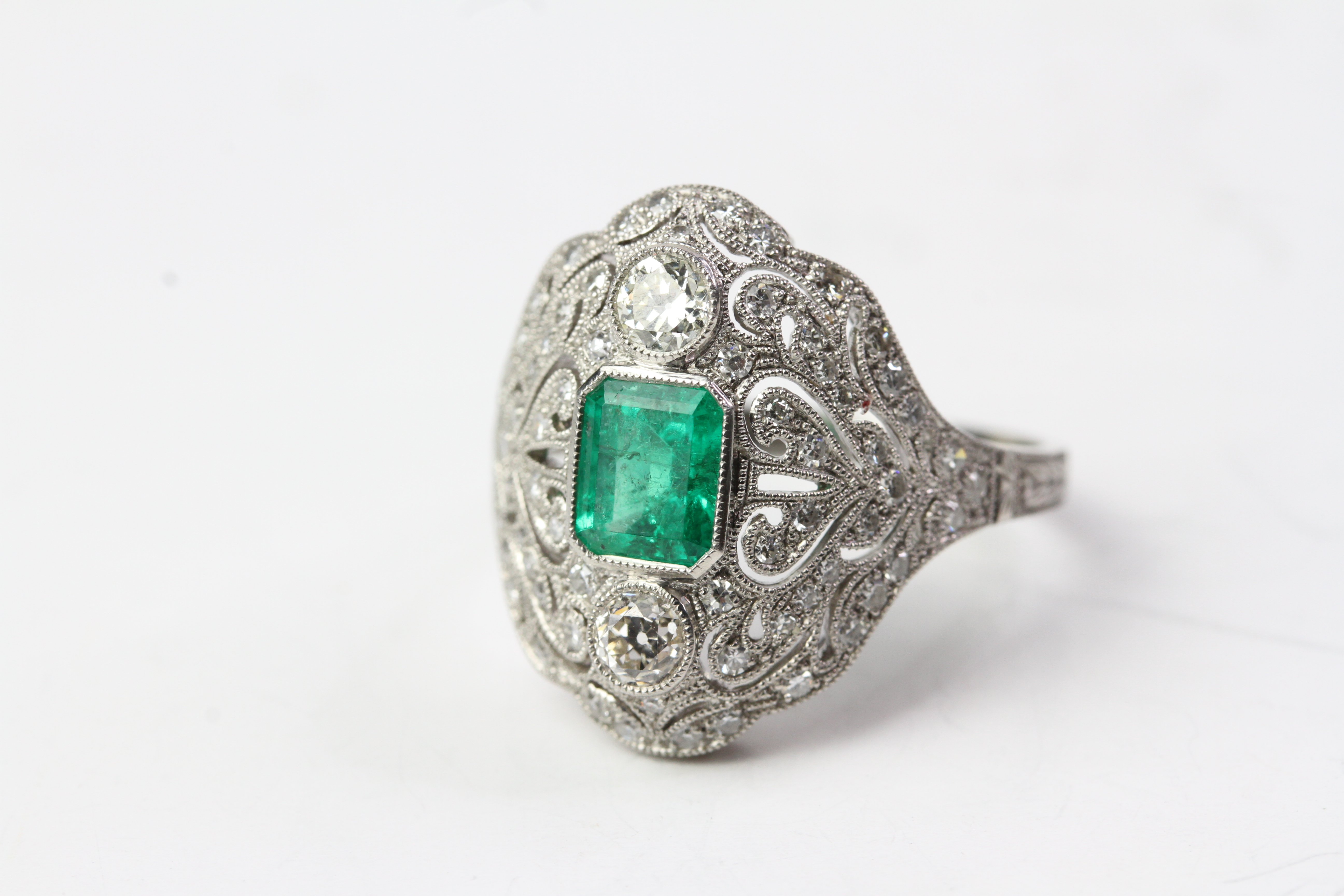 Platinum dress ring columbian emerald and diamond - bombe style with raised emerald between 2