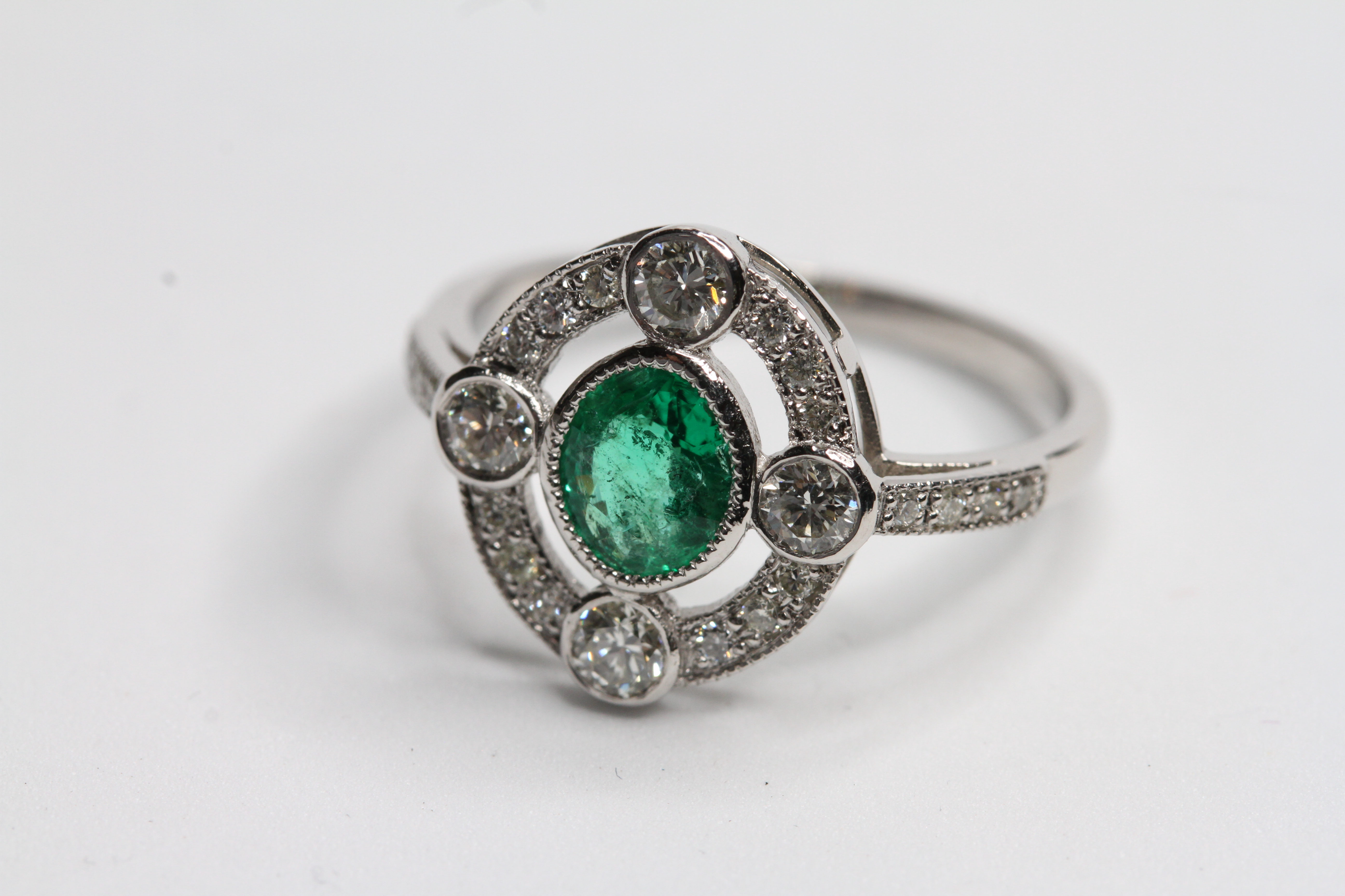 Platinum Oval Emerald and diamond ring with 4 focal point raised bezel set diamond in an open halo