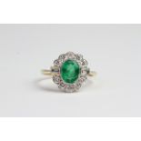 18ct Emerald and diamond ring. Central oval bezel set emerald surrounded by brilliant cut