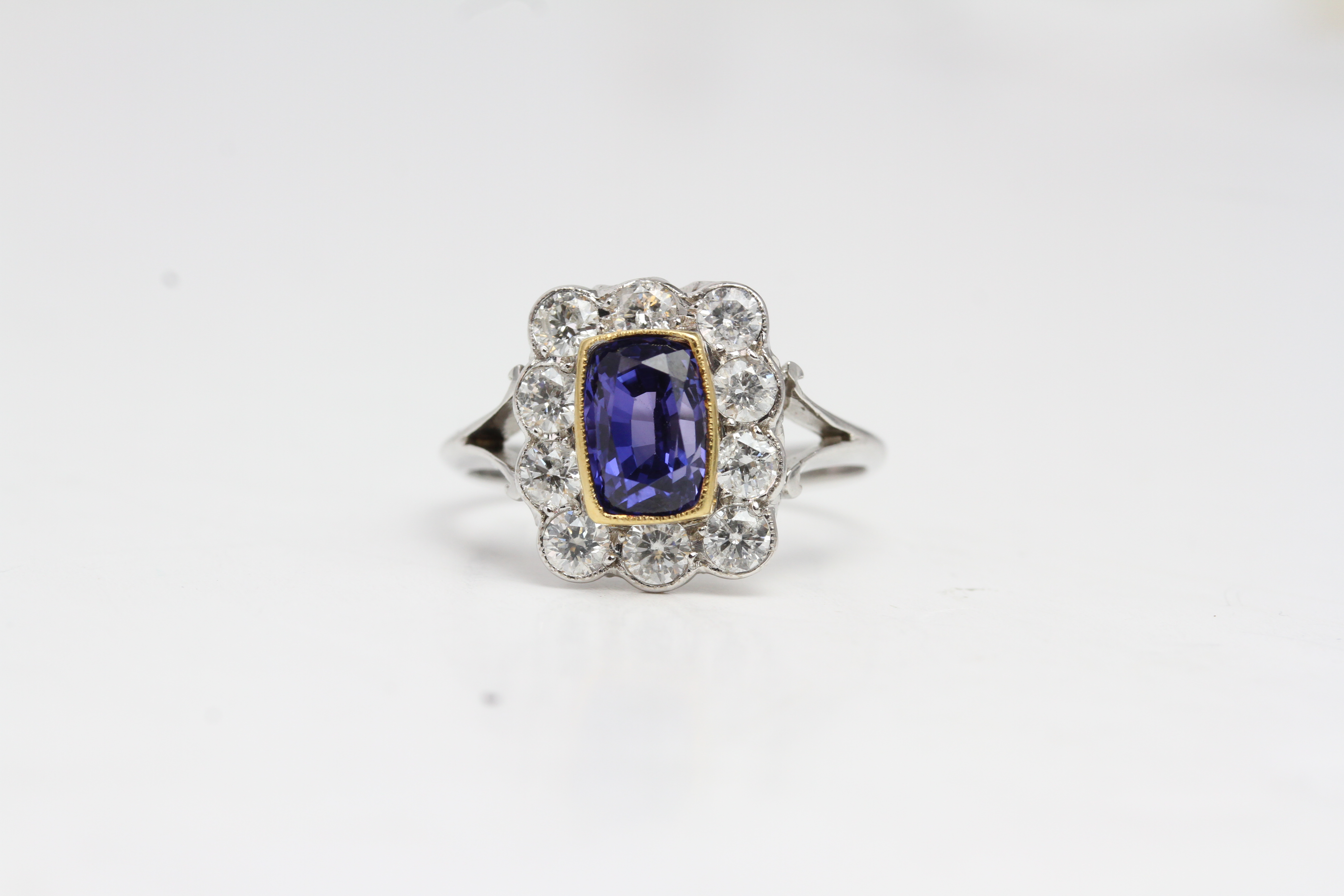 18 white gold sapphire and diamond cluster ring with split shank. The central sapphire is set in a