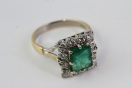 A square shaped emerald and diamond cluster ring with detailed shoulders.