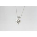 In white gold a diamond set heart suspended from a rub-over set diamond on a spectacle set diamond