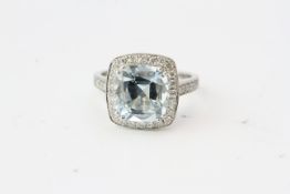 In a wedding fit style mount a cushion cut aquamarine sits proud in a halo of diamonds which