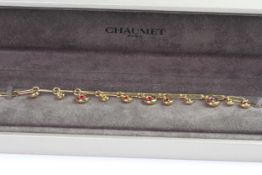 Fine 18ct gold Chaumet ruby and yellow sapphire drop charm bracelet in its original box. Measures