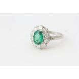An oval emerald and diamond cluster ring in platinum.Emerald 1.40 carats, Diamonds 1 carat in total,