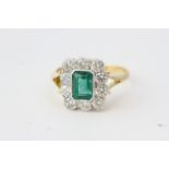 Emerald and diamond cluster ring with split shoulders in yellow gold. 10 round diamonds in the