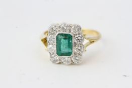 Emerald and diamond cluster ring with split shoulders in yellow gold. 10 round diamonds in the