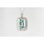 In 18 carat white cold an Emerald cut aquamarine in adiamond framed pendant with a diamond bale. The