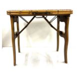 A campaign folding stool or table with rattan seat, bamboo frame, folding legs and brass carrying