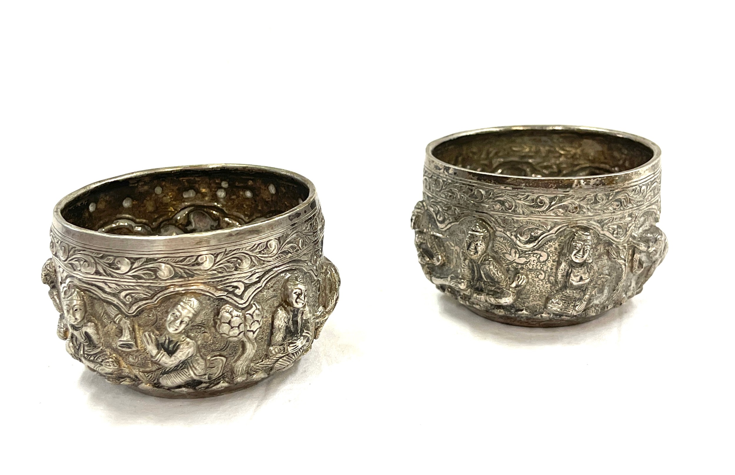 A pair of Burmese silver rice bowls embossed in high relief with Buddhas, figures, trees and