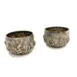 A pair of Burmese silver rice bowls embossed in high relief with Buddhas, figures, trees and