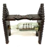 Tramp art Galleon ship in glass bottle mounted on carved wooden stand