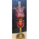 Brass oil lamp cranberry shade and font, approximate height 27 inches